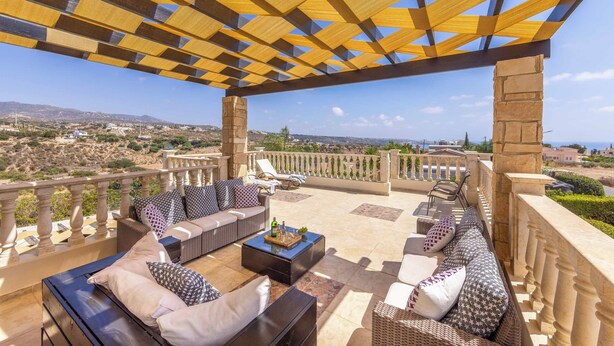 A covered outdoor seating area with wicker furniture and a stone balustrade. - Villa Cleco - Three Bedroom Villa, Sleeps 6 (Peyia)