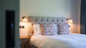 A neatly made bed with white linens and patterned pillows, flanked by two wall-mounted lamps, in a room with a simple, clean design. - The Lodge at The Yair - Riverside comfort in the Scottish Borders (By Galashiels)