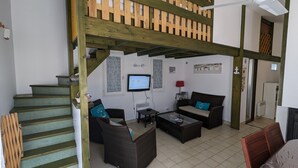 Un salon avec un escalier, un téléviseur, un canapé et une table basse.