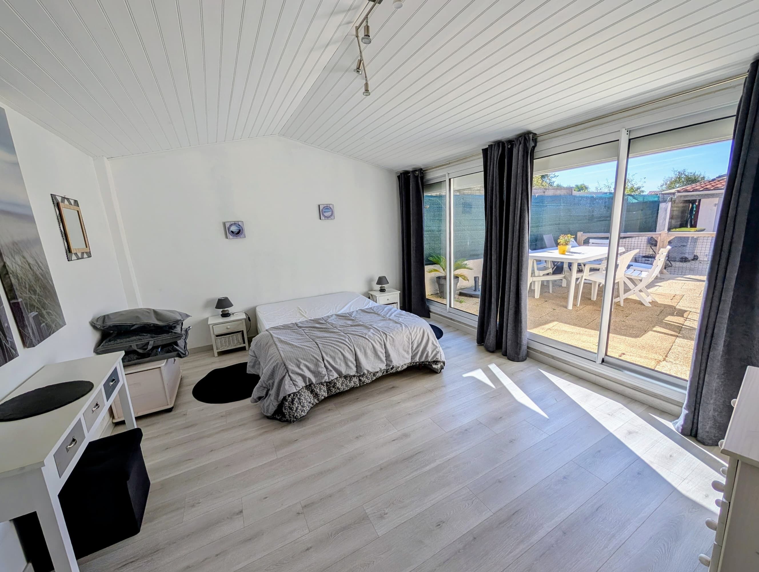 Ein modernes Schlafzimmer mit Bett, Nachttischen, einem Schreibtisch und einer großen Schiebeglasdoor, die zu einer Außenpatio führt.
