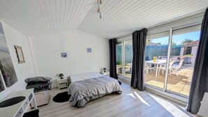 Une chambre moderne comprenant un lit, des tables de chevet, un bureau et une grande porte-fenêtre coulissante donnant sur une terrasse extérieure.