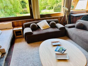 Ein modernes Wohnzimmer mit einer Couch, einem kleinen Beistelltisch und einem runden Couchtisch mit Zeitschriften.