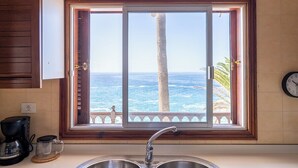 A kitchen with a large window overlooking the ocean, a sink, and a clock on the wall. - Ocean front 3 bedroom apartment (Santiago del Teide)