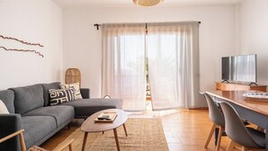 A modern living room with a grey sofa, a small round table, and a TV on a wooden stand. - Ocean front 3 bedroom apartment (Santiago del Teide)
