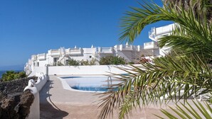 A resort with a pool, white buildings, and a clear view of the sea. - Ocean front 3 bedroom apartment (Santiago del Teide)