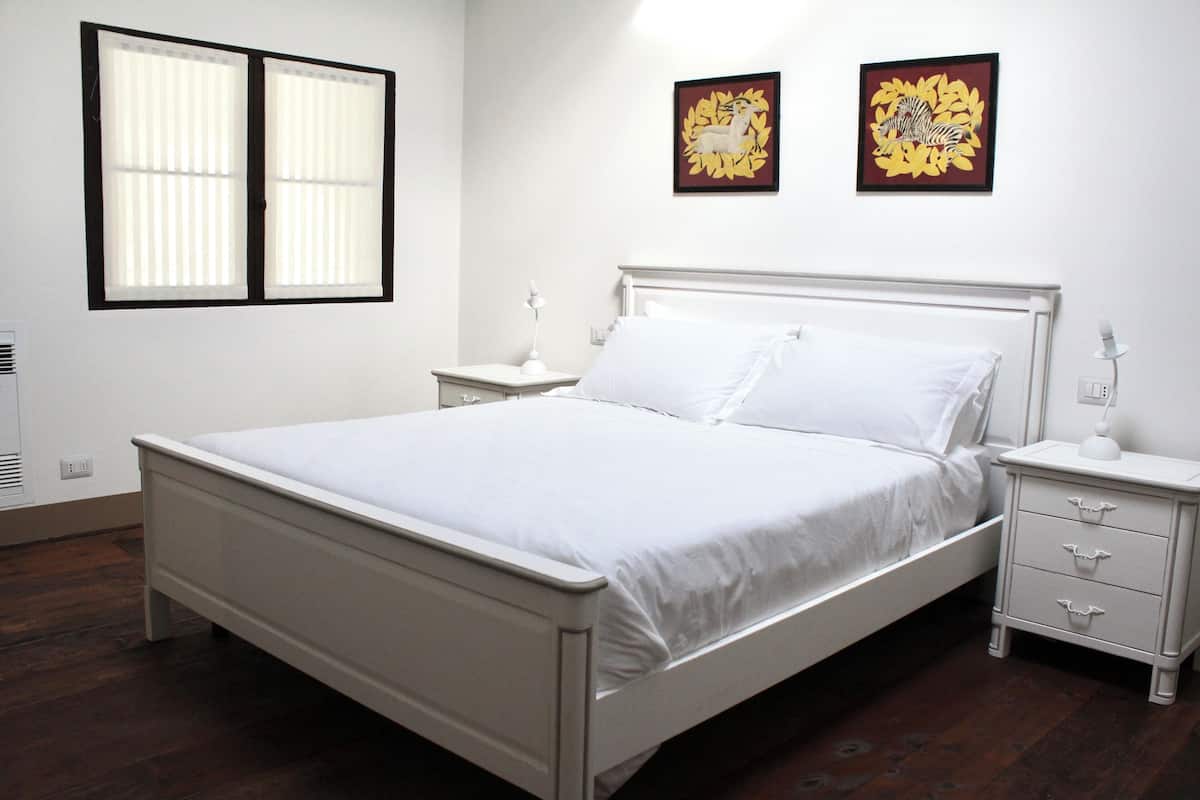 A neatly arranged bedroom with a single bed, bedside tables, and two wall-mounted artworks.