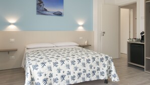 Une chambre à coucher avec un lit, un tableau accroché au mur et une table de chevet avec une lampe.