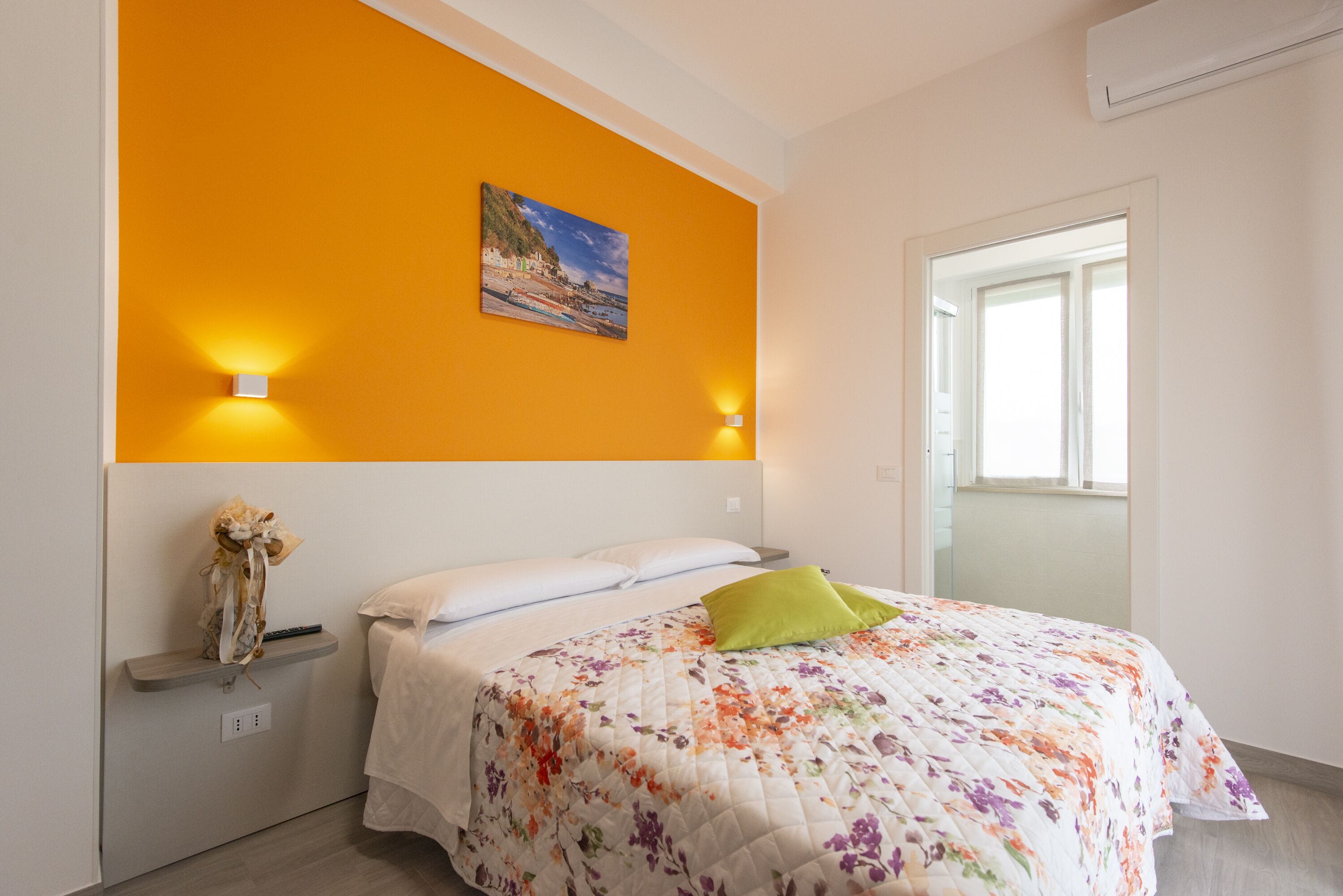 Une chambre à coucher avec un lit, un tableau au mur et deux lampes fixées au mur.