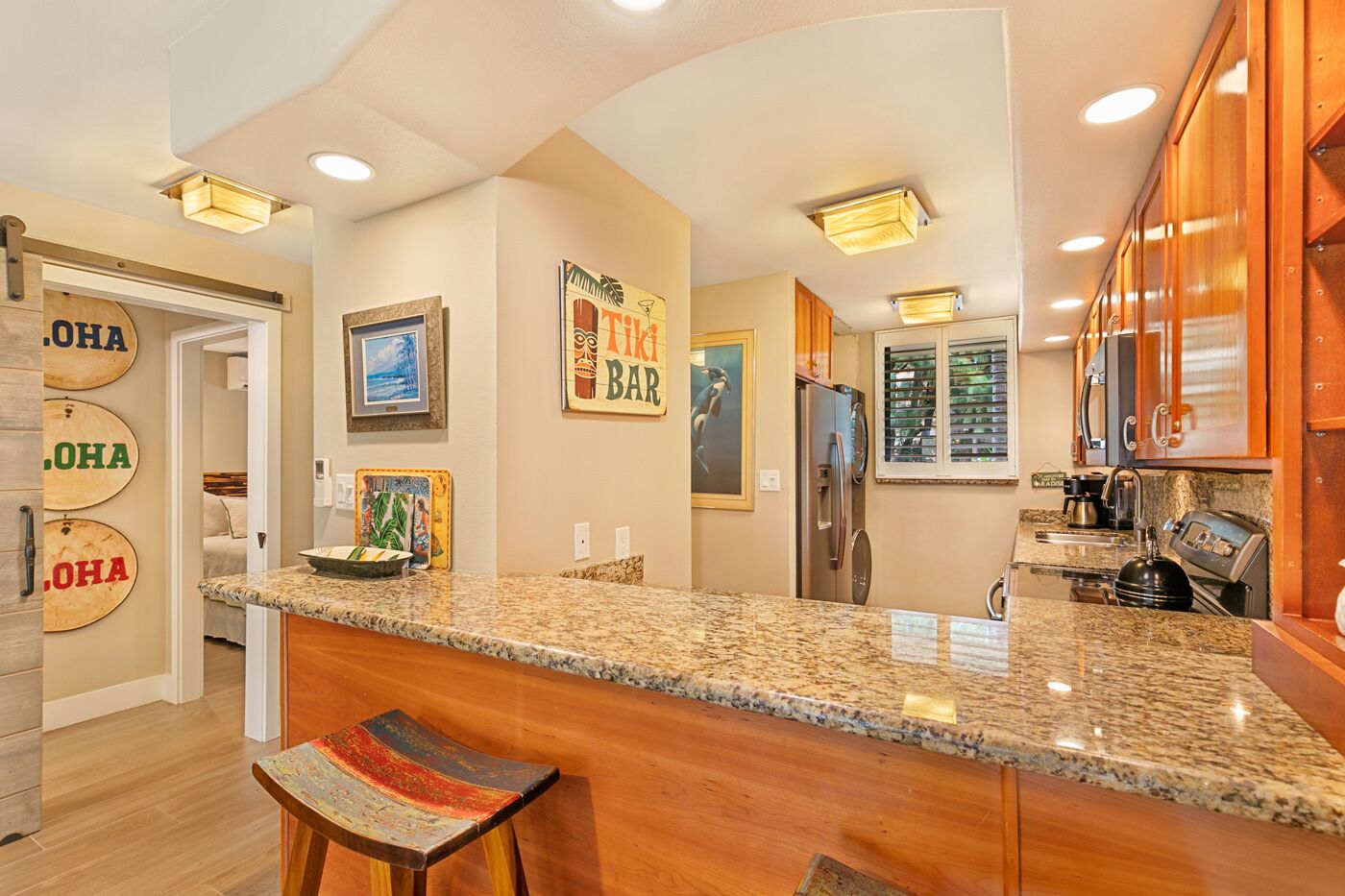 A kitchen with granite countertops, wooden cabinets, and a bar area with stools.