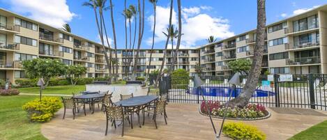 A hotel courtyard with a pool, palm trees, and outdoor seating.