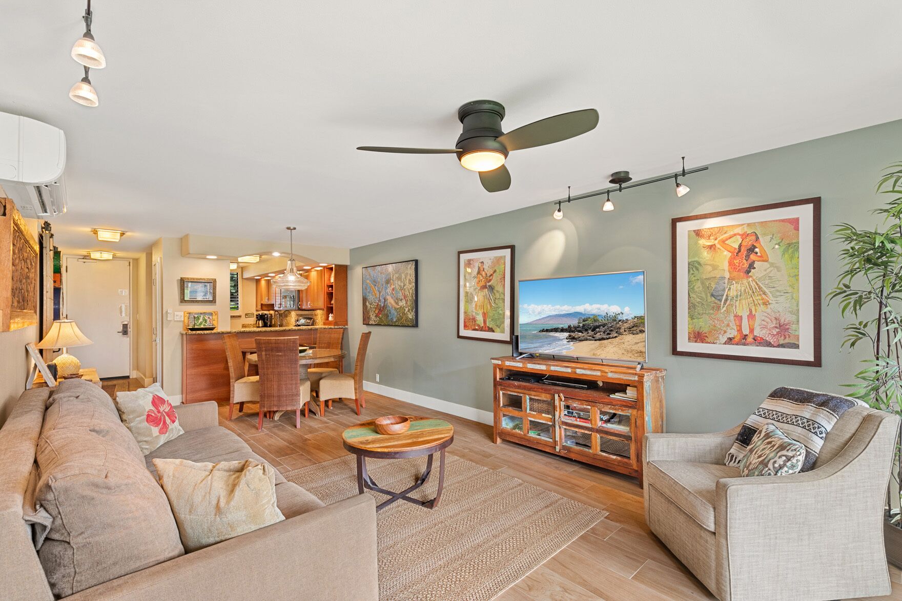 A living room with a sofa, armchairs, a coffee table, a TV, and artwork on the walls.