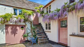 A traditional building with a stone staircase, a pink door, and purple wisteria vines. - The Old Malt House, Exton (Nr Dulverton)