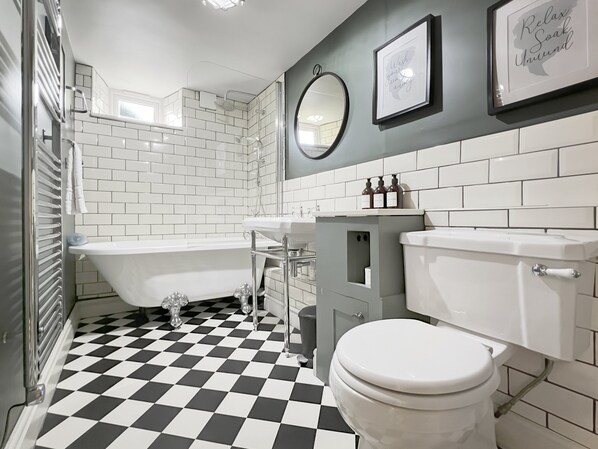 A bathroom with a checkered floor, a bathtub, a toilet, and a sink.