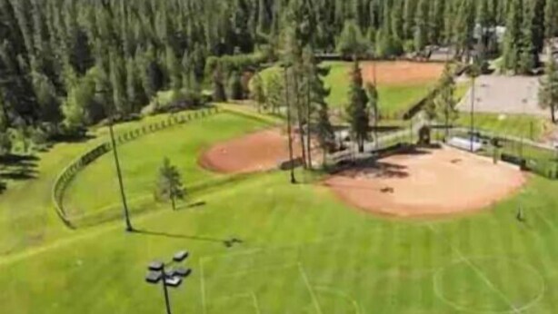 Un campo de béisbol con vistas despejadas al bosque y las montañas circundantes.