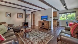 Un salón amplio con chimenea, sofás de cuero, una alfombra grande y un televisor.