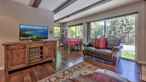 Un salón amplio con un televisor grande, mueble de entretenimiento de madera y un sofá de cuero.