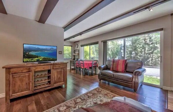 A spacious living room with a large TV, wooden entertainment unit, and a leather couch.