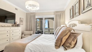 Een hotelkamer met een groot bed, een televisie, een dressoir en een balkon met uitzicht op zee.
