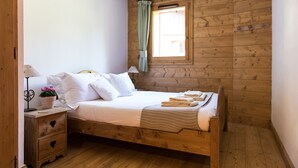 Ein Schlafzimmer mit Holzwandverkleidung, einem Bett, Nachttischen, einem Fenster mit Vorhängen und einer Hängelampe.