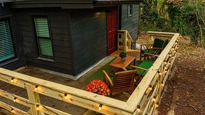 A wooden deck with string lights, a small table, and chairs. - walk to square! Cozy 2 BR bungalow, moody design (Dahlonega)