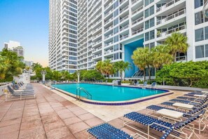 Um hotel com piscina, espreguiçadeiras e palmeiras.