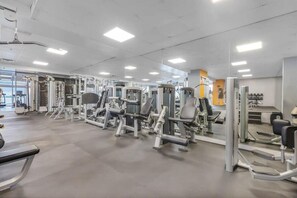 Uma academia com diversos aparelhos de exercícios, espelhos e um ambiente limpo e bem iluminado.