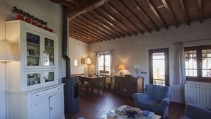 A cozy living room with a wooden ceiling, a dining area with a table and chairs, and a seating area with two sofas. - Casa Pedona (Camaiore)