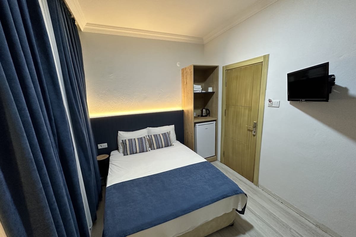 A hotel room with a bed, a television, a wardrobe, and a small kitchenette.