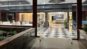 A hotel reception area with a checkered floor, glass doors, and a reception desk. - Enda Lara Hotel (Antalya)