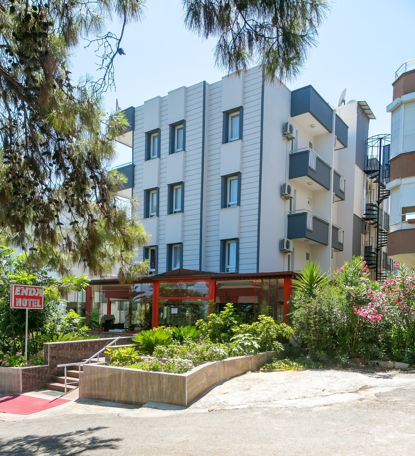 A multi-story hotel with a modern design, featuring a covered entrance and a landscaped garden area.