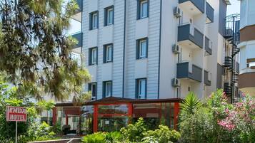 A multi-story hotel with a modern design, featuring a covered entrance and a landscaped garden area.