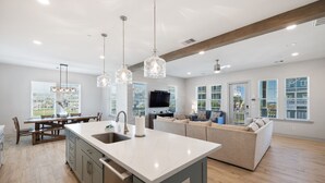 Una cocina moderna con una isla grande, mesa de comedor de madera y electrodomésticos integrados.
