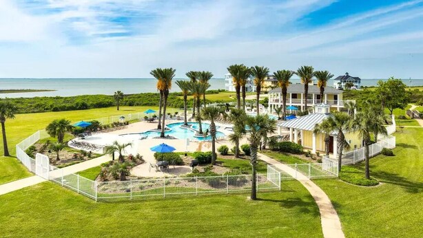 Un resort con piscina, palmeras y vistas al océano.