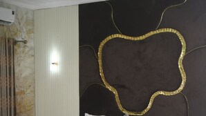 A hotel room with a bed, a red chair, a wall-mounted air conditioner, and a ceiling light fixture. - Joclarif Hotel (Zaria)