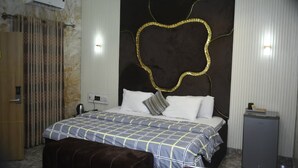 Une chambre d’hôtel équipée d’un lit, d’une banquette, d’un petit bureau et d’un appareil de climatisation.