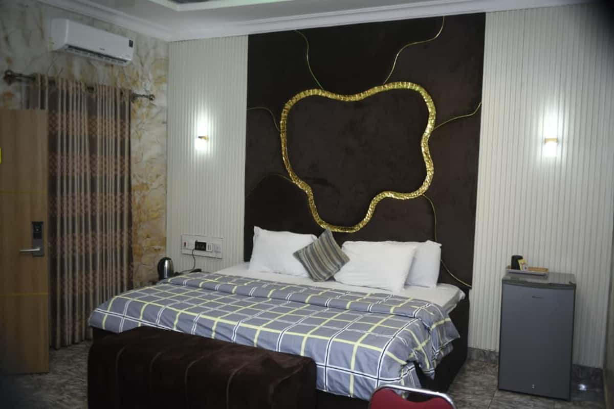 Une chambre d’hôtel équipée d’un lit, d’une banquette, d’un petit bureau et d’un appareil de climatisation.