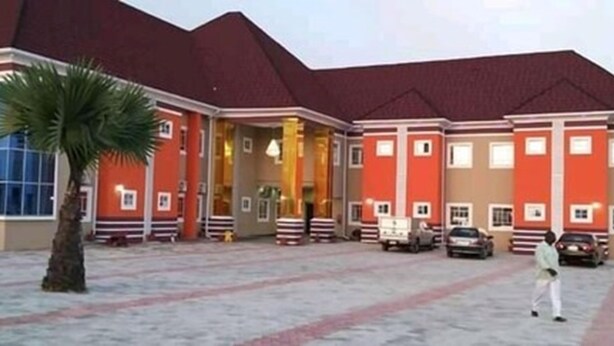 A building with a red and beige facade, multiple windows, and a central entrance. - Joclarif Hotel (Zaria)