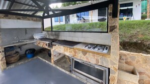 An outdoor kitchen with a stone wall, a grill, a sink, and a built-in oven. - Finca Villa Maju & Finca Villa Maju km24 (Dagua)