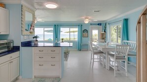 A bright kitchen with a large island, white cabinetry, and a view of the ocean. - Charming Two Story House located directly on Melbourne Beach. (Melbourne Beach)