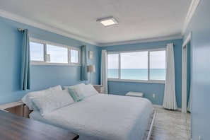 Una camera da letto con un letto, un comodino, una lampada e vista sull'oceano.