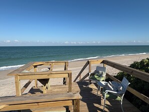 Un terrazzo in legno con un tavolo e due sedie affacciato su una spiaggia.