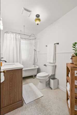 A bathroom with a white sink, wooden vanity, white toilet, and a bathtub with a shower curtain.