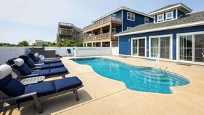 A pool area with lounge chairs, a swimming pool, and a building with balconies. - Newly Renovated Semi-Oceanfront Duck Home w/Pool (Duck)