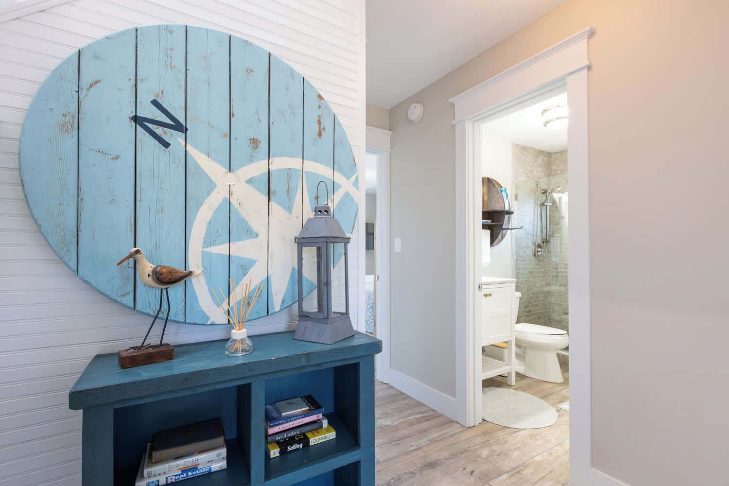 A room with a large circular wall decoration, a small shelf with books, a bird sculpture, and a lantern.