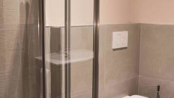 Une salle de bain moderne avec une douche à parois de verre, un bidet et des toilettes.