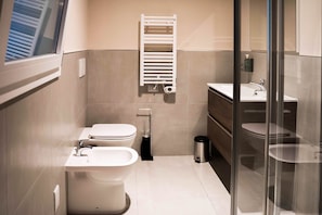 A modern bathroom with a toilet, bidet, and sink.