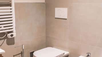 A modern bathroom with a toilet, bidet, and a towel rack.