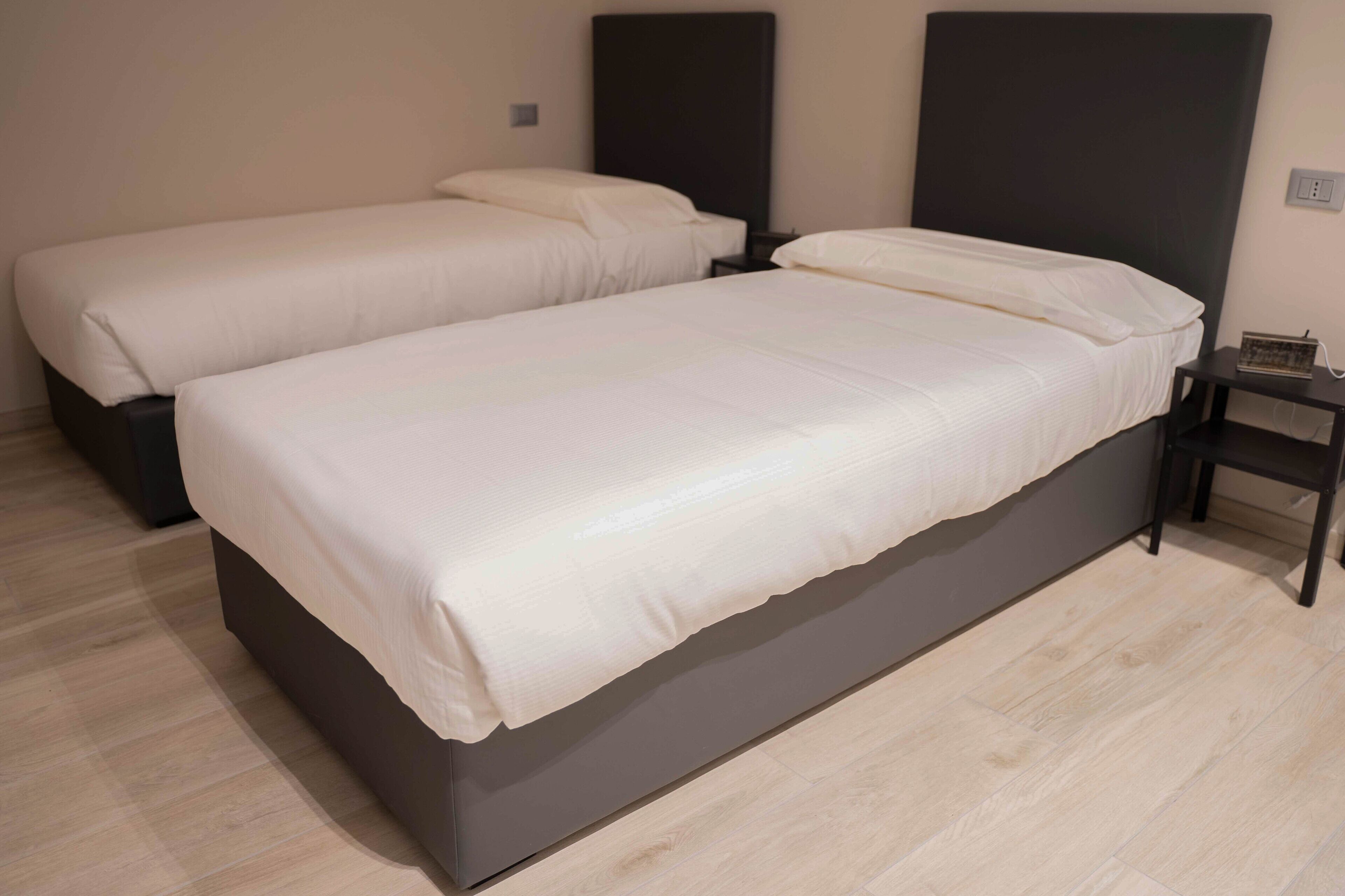 A hotel room with two beds, a bedside table, and a nightstand.