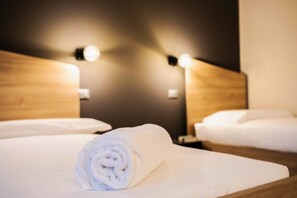 A hotel room with two beds, each with a wooden headboard and white bedding.