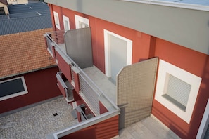 A red building with a balcony, a window, and a door.